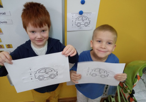 Dwóch chłopców prezentuje wykonane zadanie daltońskie.